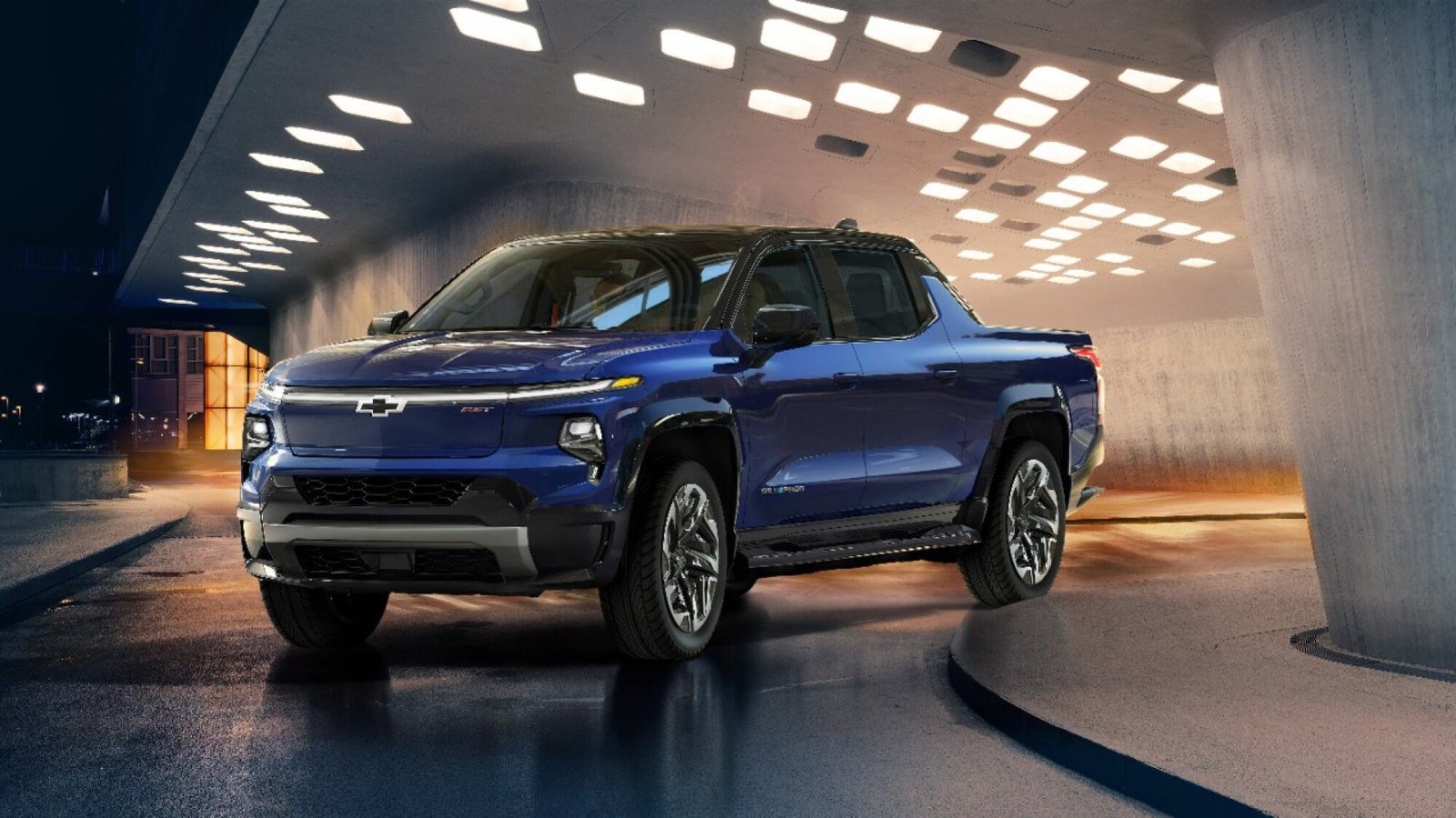 A blue truck on a slick road with lights above it.