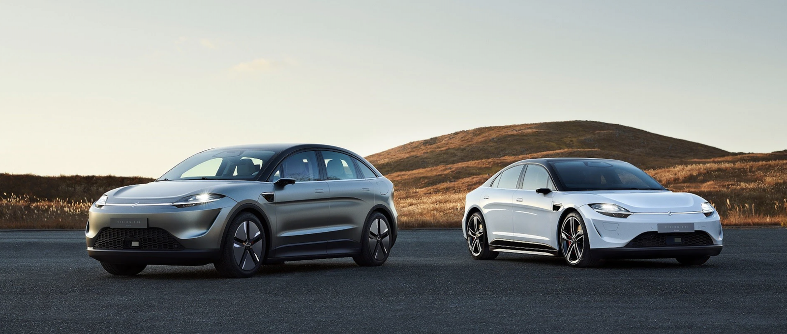 A concept electric SUV next to a concept EV sedan on a road with a mountain in the background.