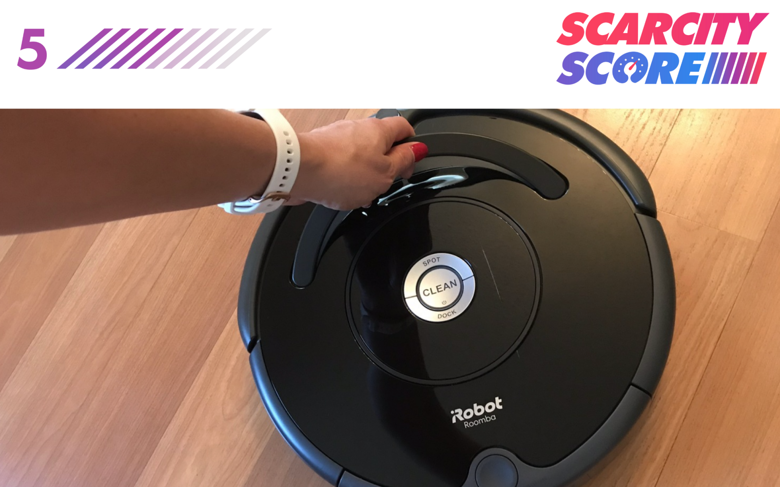 a hand reaches for the iRobot Roomba robot vacuum